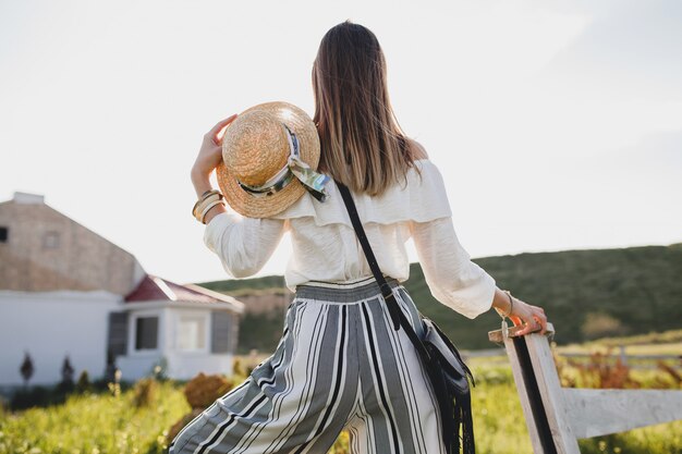 Giovane donna con cappello di paglia in campagna