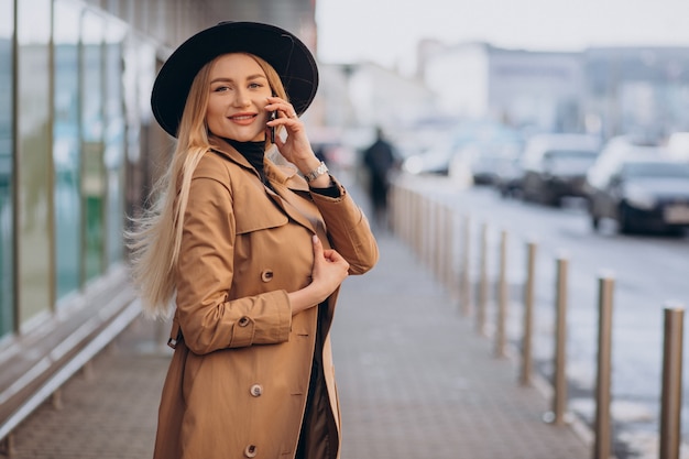 Giovane donna con cappello nero utilizzando il telefono