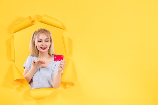 Giovane donna con carta di credito su carta gialla strappata superficie denaro banca vendita shopping