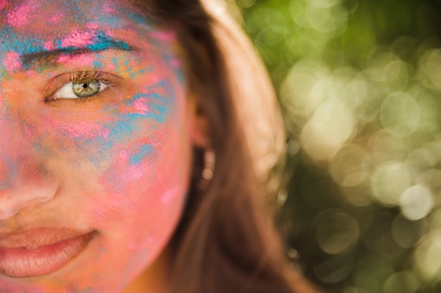 Giovane donna con colore holi rosa e blu sul suo viso