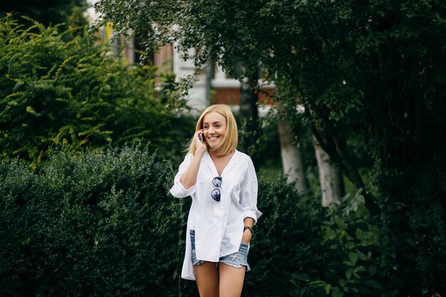 Giovane donna con computer portatile e smart phone. Bella ragazza studente che lavora al computer portatile all&#39;aperto