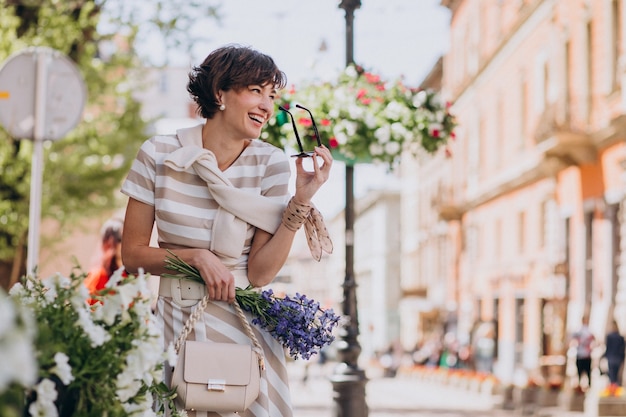 Giovane donna con fiori che cammina in città