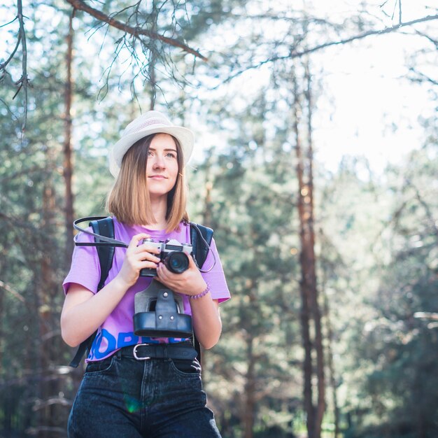 Giovane donna con fotocamera nella foresta