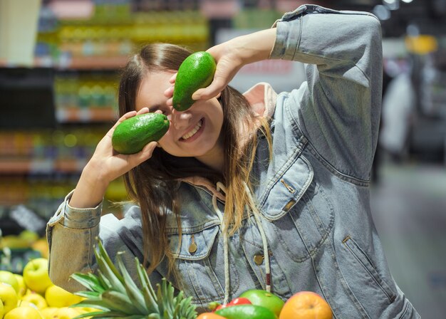 Giovane donna con frutta in mano al supermercato.