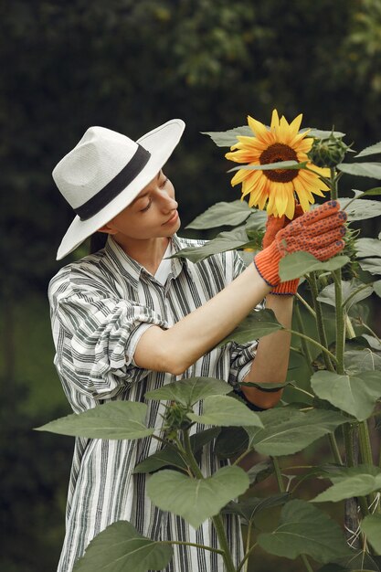 Giovane donna con girasoli. Signora con un cappello. Ragazza in un giardino.