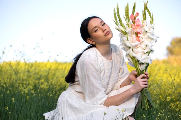 Giovane donna con gladiolo in natura