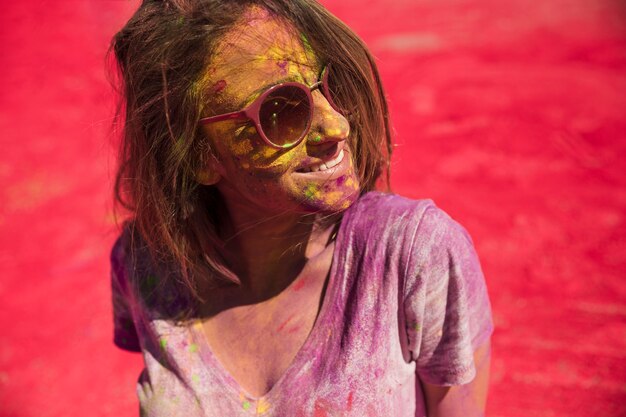 Giovane donna con gli occhi chiusi coperti di polvere che si trova sul colore rosso holi