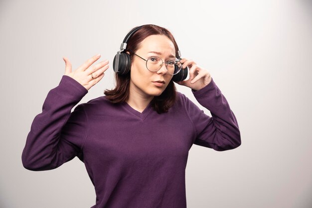 Giovane donna con gli occhiali che ascolta musica in cuffia su un bianco. Foto di alta qualità