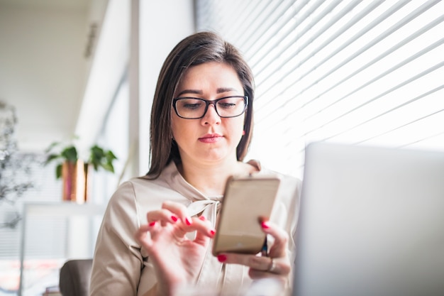 Giovane donna con gli occhiali con il cellulare