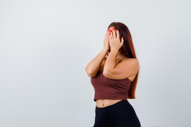 Giovane donna con i capelli lunghi che indossa abbigliamento sportivo che copre il viso
