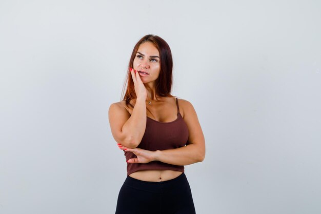 Giovane donna con i capelli lunghi in un top corto marrone