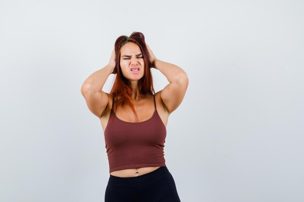 Giovane donna con i capelli lunghi in un top corto marrone