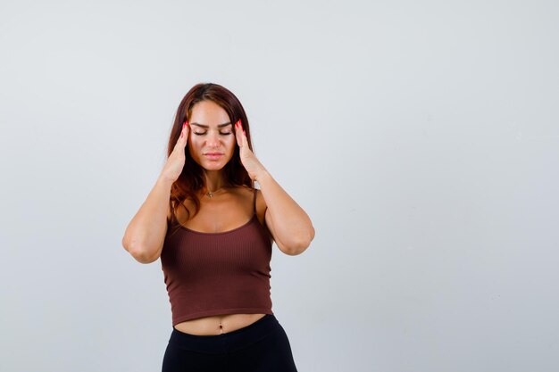 Giovane donna con i capelli lunghi in un top corto marrone