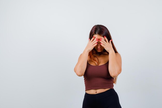 Giovane donna con i capelli lunghi in un top corto marrone