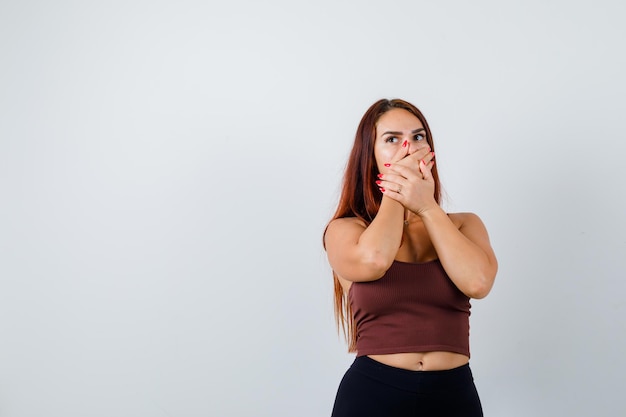 Giovane donna con i capelli lunghi in un top corto marrone