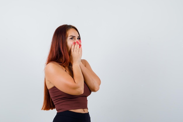 Giovane donna con i capelli lunghi in un top corto marrone