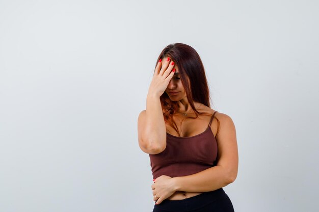 Giovane donna con i capelli lunghi in un top corto marrone