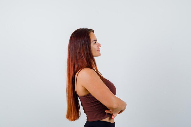 Giovane donna con i capelli lunghi in un top corto marrone
