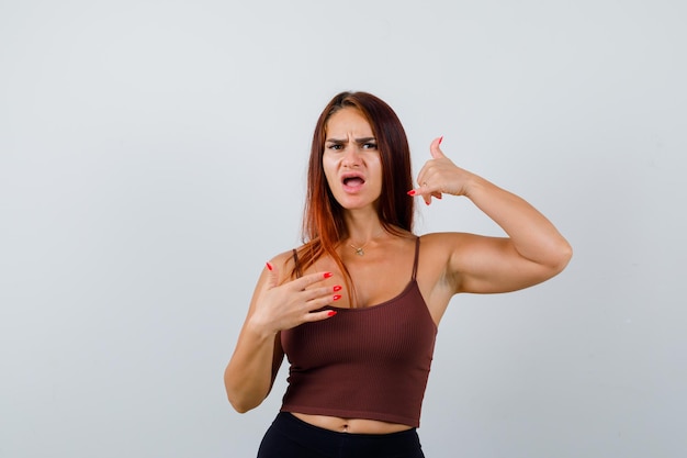 Giovane donna con i capelli lunghi in un top corto marrone