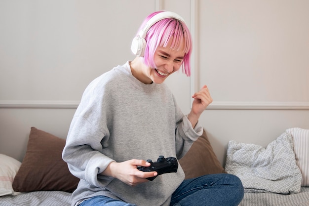 Giovane donna con i capelli rosa che gioca a un videogioco