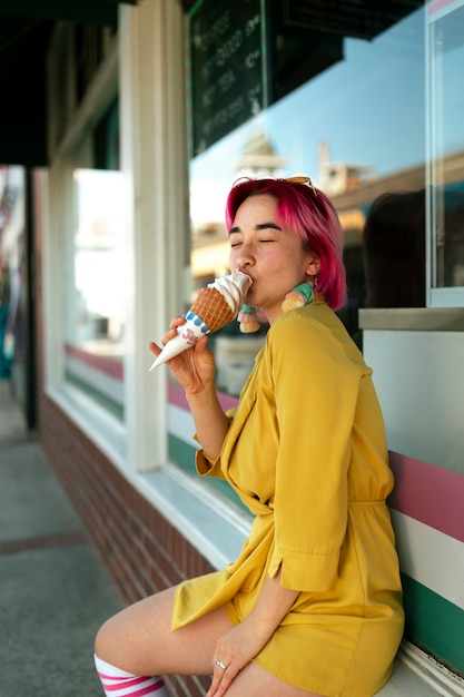 Giovane donna con i capelli tinti che mangia il gelato