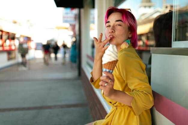 Giovane donna con i capelli tinti che mangia il gelato