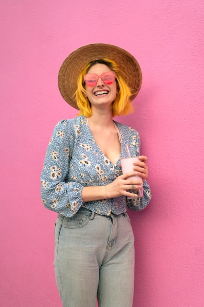 Giovane donna con i capelli tinti vicino al muro rosa