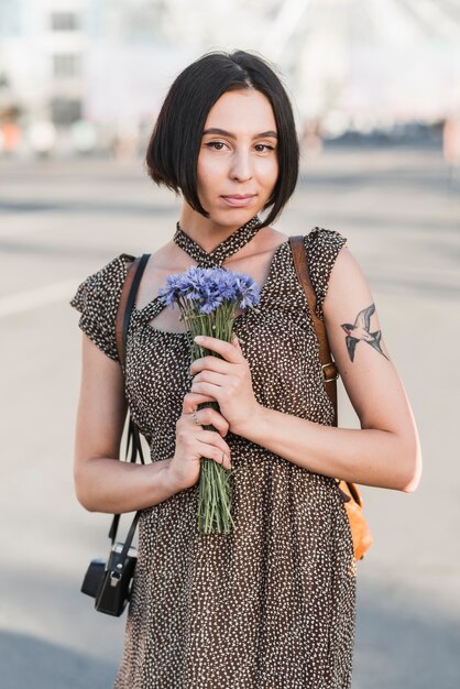Giovane donna con i fiori della holding del tatuaggio