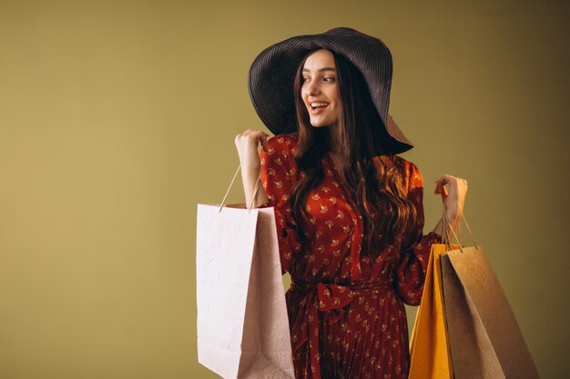 Giovane donna con i sacchetti di shopping in un bel vestito e cappello