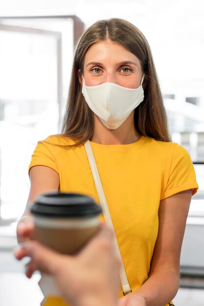 Giovane donna con il caffè d'acquisto della maschera