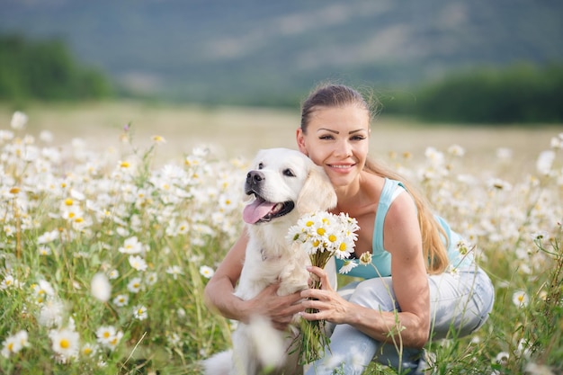 Giovane donna con il cane in un campo di camomilla