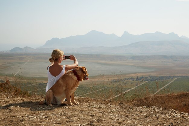 Giovane donna con il cane in una giornata di sole seduto in alta montagna