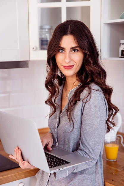 Giovane donna con il portatile in cucina