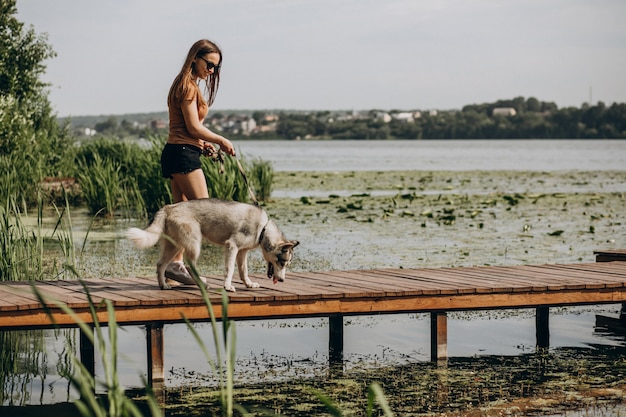 Giovane donna con il suo cane husky sul lago