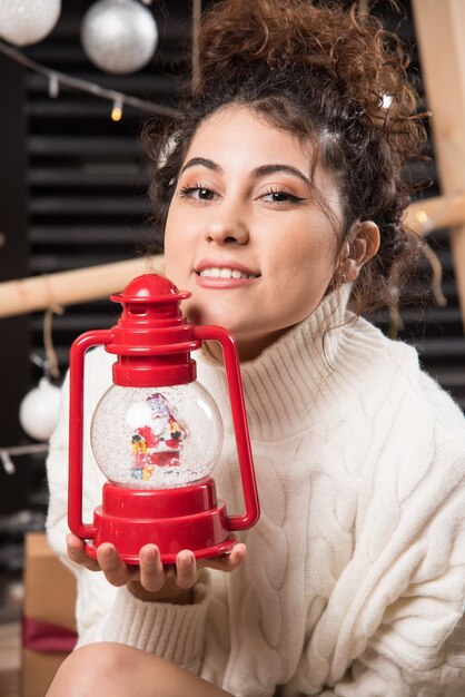 Giovane donna con in mano una lampada di Natale rossa