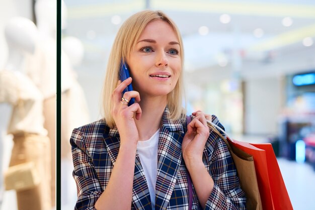 Giovane donna con le borse della spesa piene che parla al cellulare