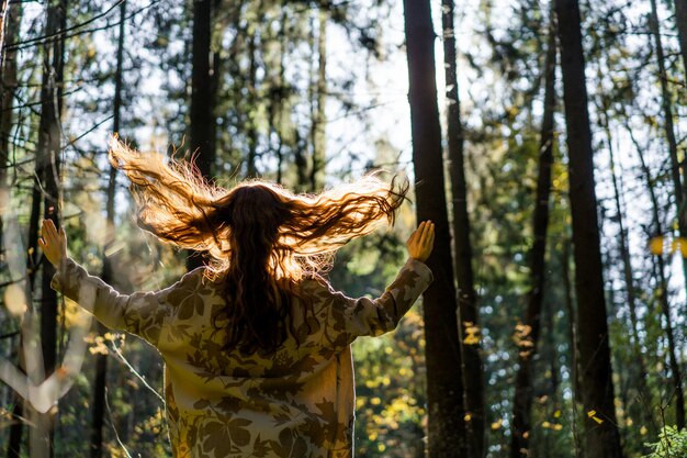 Giovane donna con lunghi capelli rossi in un vestito di lino raccolta funghi nella foresta