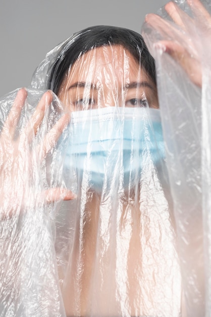 Giovane donna con mascherina medica ricoperta di plastica