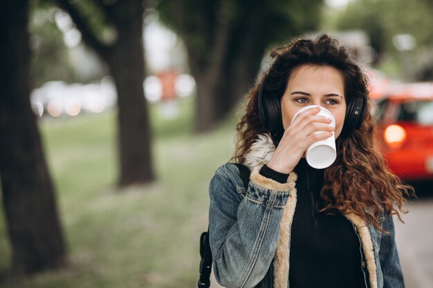 Giovane donna con musica d'ascolto e bere caffè