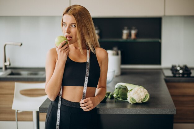 Giovane donna con nastro di misurazione in cucina