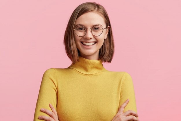 Giovane donna con occhiali rotondi e maglione giallo