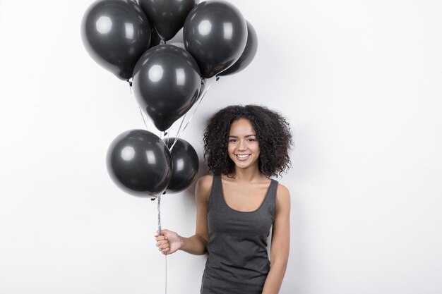 Giovane donna con palloncini neri su uno sfondo bianco girato in studio