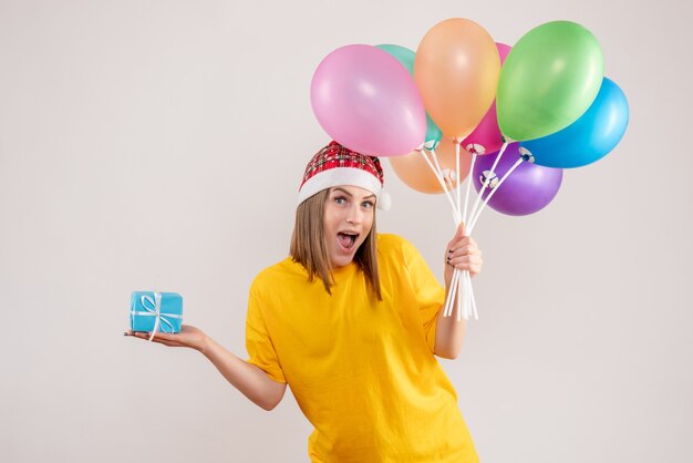 giovane donna con poco presente e palloncini colorati su bianco