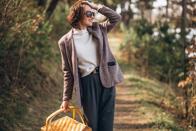 Giovane donna con scatola da picnic nella foresta