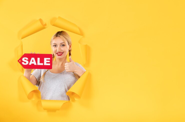 Foto gratuito giovane donna con segno di iscrizione di vendita su sfondo di carta gialla strappata shopping al coperto
