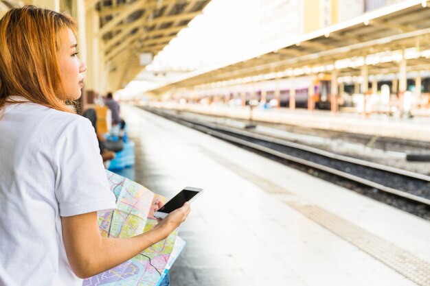 Giovane donna con smartphone e mappa