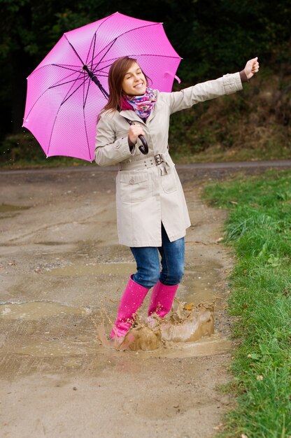 Giovane donna con stivali di gomma si diverte in una giornata piovosa