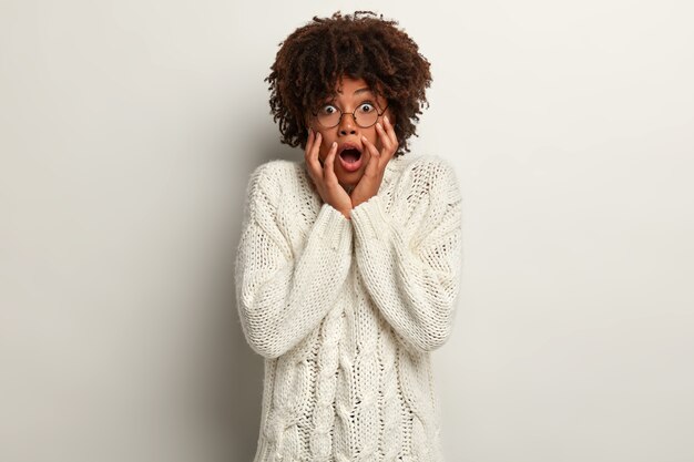 Giovane donna con taglio di capelli afro che indossa un maglione bianco