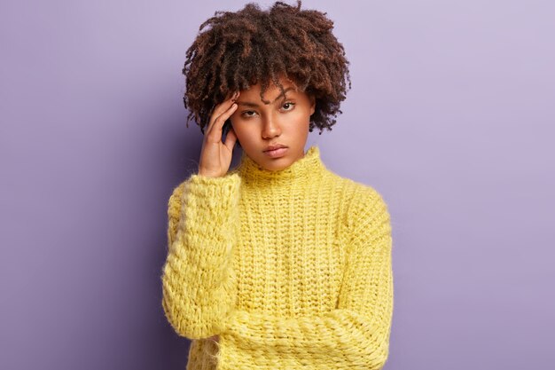 Giovane donna con taglio di capelli afro che indossa un maglione giallo