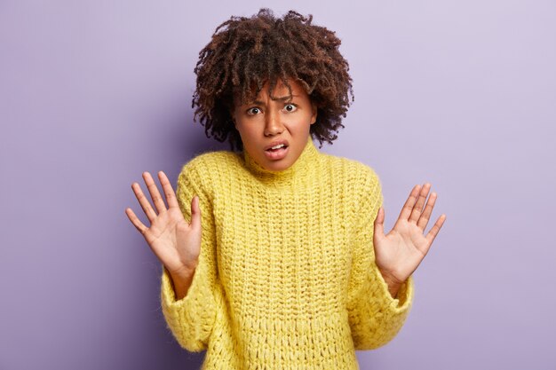 Giovane donna con taglio di capelli afro che indossa un maglione giallo